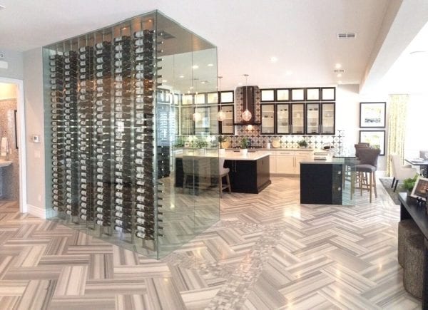 a wide angle view of a glass wine cellar in the middle of a luxurious kitchen