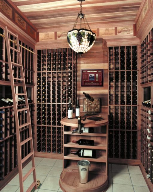 an image of a full wood wine cellar with a small table in the middle and a wooden ladder for easy wine access