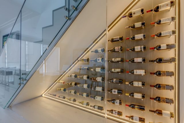 an all-glass wine display under the stairs of a residence