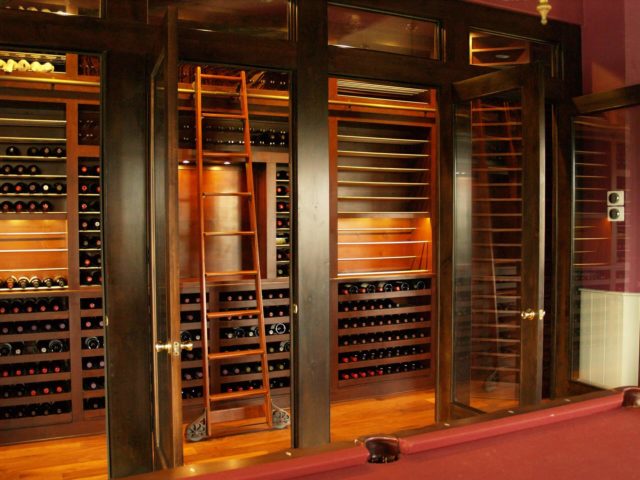 Walnut Wood Wine Cellar with Ladder behind Custom Door with Side Lights in Bee Cave, TX