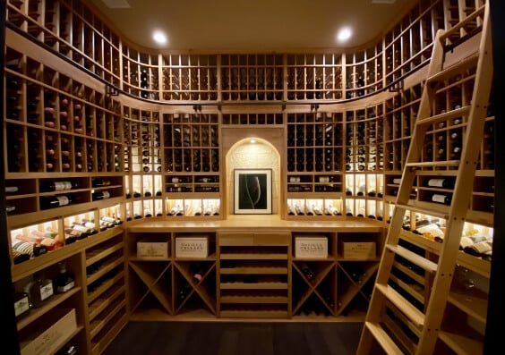 a wide-angle view of a full wood wine cellar with a ladder